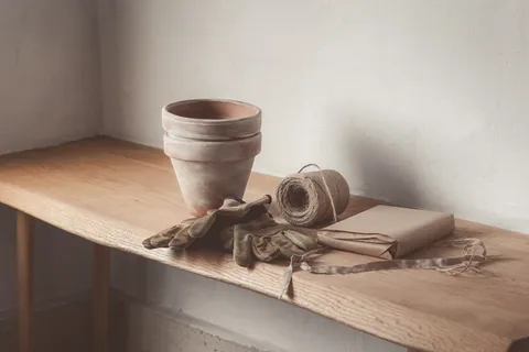 Empty terracotta pots, twine and gloves on a potting bench.