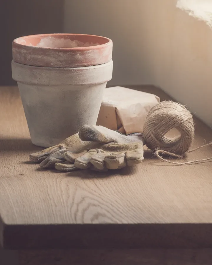 Empty terracotta pots, twine and gloves on a potting bench.