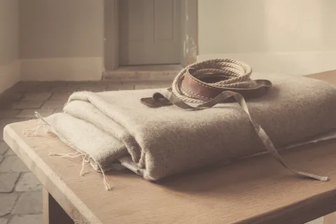 A folded wool blanket and a coiled lead on a stone-flagged floor.