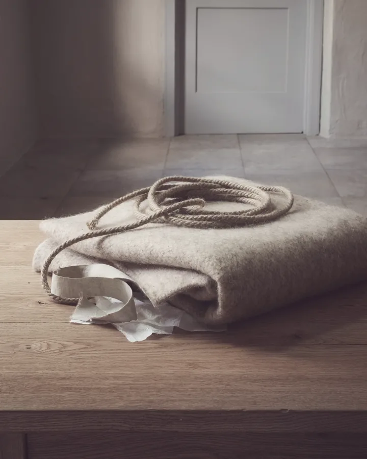 A folded wool blanket and a coiled lead on a stone-flagged floor.