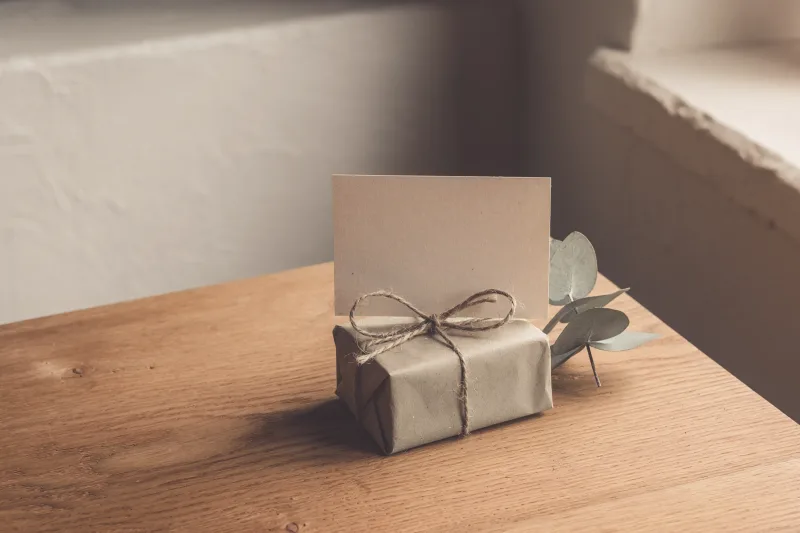 A small parcel tied with twine and a blank card on an oak table